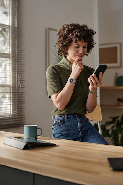A person sitting at a desk, looking concerned while viewing their smartphone. The phone shows a news article about a recent data breach on a social media platform. The background is a typical home setting with books and a laptop.